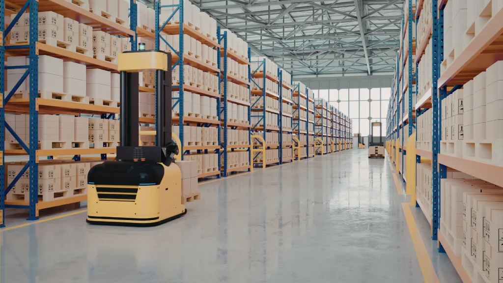 Automated yellow warehouse robot drives along a wide aisle between tall blue metal shelving with stacked boxes and pallets.